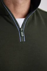 Sweater color beige de tejido elastizado de algodón y poliéster, con medio cierre en el cuello, detalles de tela de algodón al tono y tirador de eco cuero.