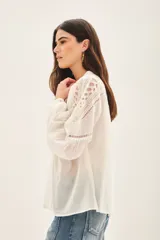 Camisa blanca de algodón con corte amplio, bordado a tono en canesú delantero, trasero y hombros. Mangas largas con volumen y elástico en los puños.