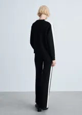 Pantalón de punto fino negro con raya lateral blanca, tiro medio, diseño recto y largo.