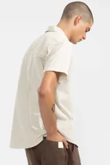 Camisa de manga corta color crema, confeccionada en algodón ligero con textura waffle. Tiene corte cuadrado, bolsillo en el pecho y botones de coco grabados con el logo de Polonio.