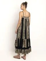 Vestido largo color crema con estampado dorado, de breteles finos y escote en V. Presenta una silueta amplia con caída fluida y detalle de volado en el ruedo.