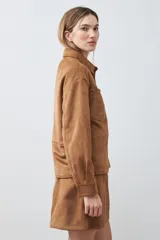 Chaqueta color tostado simil gamuza con cuello clásico, cierre con botones a presión, bolsillos de parche en el pecho y corte recto.