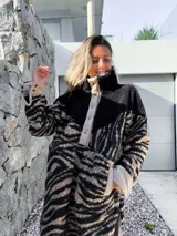 Buzo de polar con cuello alto, cierre de botones a presión y estampado de cebra en tonos beige y negro.