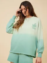 Sweater color crema con degradé a naranja, con cuello redondo y logo estampado de palmera en el pecho.