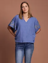 Blusa color beige de crepe marca Batía, con cuello a la base y escote en V. Presenta mangas cortas amplias con bordados.