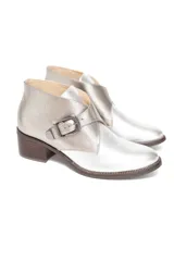 Botín plateado de cuero con efecto metalizado, corte lateral en forma de V y ajuste con hebilla. Tiene taco de madera bajo.