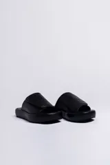 Sandalia negra de cuero vacuno con plataforma gruesa forrada en napa. Presenta una tira ancha con textura gofrada y cierre de velcro ajustable.