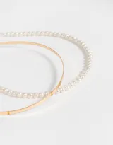 Set de dos vinchas rígidas para el pelo, una dorada lisa y otra con apliques de perlas.