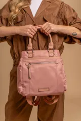 Mochila color rosado, con asas superiores y correas ajustables para llevar como mochila. Cuenta con un compartimento principal amplio y un bolsillo frontal con cierre.