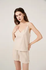 Conjunto de pijama de satén a rayas verticales color beige, compuesto por un top con breteles finos y escote en V, y un short de calce holgado.