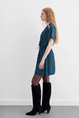 Minivestido negro de escote cruzado, mangas cortas y cintura elastizada con lazo. Presenta cadenitas metálicas en los hombros y en los extremos del lazo.