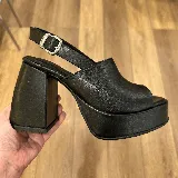 Sandalias negras de cuero sintético con plataforma y tacón cuadrado. Tira delantera ancha y tira trasera con hebilla ajustable.