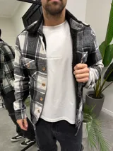 Chaqueta de paño a cuadros blancos y negros con forro interior de corderito sintético negro, cuello camisero y cierre frontal con botones de madera.