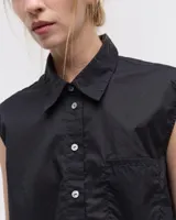 Camisa blanca sin mangas confeccionada en voile de algodón liviano. Tiene cuello camisero, cartera con botones de nácar, bolsillo plaqué en el delantero, costura en centro espalda y recorte en cintura trasera con tajo que se superpone. El ruedo es escalonado, más corto adelante.