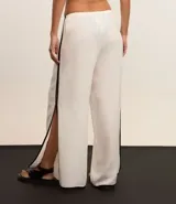 Pantalón de playa de lino y viscosa color blanco, con rayas laterales a contratono, cintura elastizada y lazo ajustable.