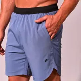 Short deportivo de hombre color celeste con cintura elástica negra, cordón de ajuste interno, bolsillos laterales y logo estampado en la pierna.