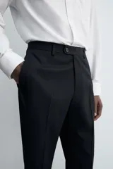 Pantalón de vestir negro de lana, corte recto, con bolsillos laterales y traseros de ojal con botón.
