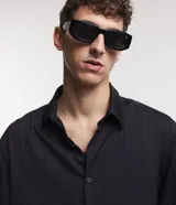 Camisa negra de poliéster con cuello inglés, manga larga, abotonada adelante y textura con rayas verticales.