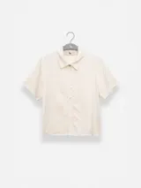 Camisa manga corta color marrón confeccionada en una mezcla de lino y tencel, con cuello camisero y cierre abotonado al frente.