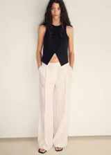 Vestido largo negro con chaleco incorporado, sin mangas y con abertura triangular en el abdomen.