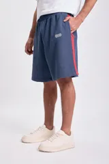 Short deportivo de tela de algodón, color azul marino, con franjas laterales rojas. Tiene cintura elástica y corte holgado.