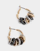 Aros tipo argolla dorados con dijes de arandelas en dorado, plateado y negro.