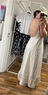 Vestido largo de algodón color blanco con estampado de lunares pequeños en color marrón. Presenta tirantes finos y escote pronunciado en la espalda. El ruedo tiene un volante con fruncido.