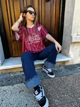 Remerón negro con estampado de rayas verticales blancas y logo de equipo de béisbol en el frente.