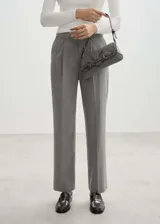 Pantalón de vestir gris con trabillas, tiro medio, bolsillos laterales, cierre oculto de botón, gancho y cremallera, diseño recto, pinzas, diseño largo y bolsillo de ribete en la parte posterior.
