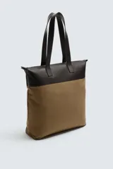Bolso tipo shopper de tela color marrón con detalles en cuero color marrón oscuro. Tiene doble asa de mano de cuero y cierre principal con cremallera.