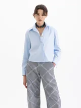 Camisa blanca de manga larga con cuello clásico y botones de diferentes colores.