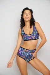 Conjunto de bikini estampado con motivos abstractos en tonos rosa, fucsia, verde y amarillo. El corpiño es de corte deportivo con breteles anchos y el calzón es de tiro alto con cintura elástica.