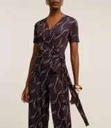 Mono largo de microfibra con estampado geométrico en tonos marrones y blancos. Tiene escote en V, mangas cortas y lazo ajustable en la cintura.