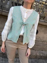 Chaleco reversible con escote en V y lazo para ajustar, confeccionado en lino italiano con sutil brillo. Un lado es a cuadros en tonos verde agua y amarillo, y el otro es liso color crudo.