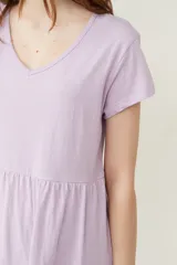 Vestido corto lila con cuello en V y mangas cortas. Tiene corte holgado y dos volados en la falda.