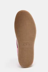 Zapatillas deportivas rosas de gamuza con detalles en blanco y suela color caramelo. Cierre con cordones y suela de 2,5 cm de altura.