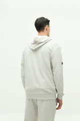 Canguro de felpa color hueso, con capucha ajustable, cordones y logo estampado en el pecho.