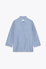 Camisa de cuello solapa y manga tres cuartos con rayas verticales azules y blancas. Cierre frontal con botones ocultos.