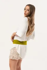 Camisa blanca de silueta oversize, con cuello camisero, manga 3/4 y corte más largo en la espalda. Presenta bordados de coral y caracol en el frente, y botones a tono.