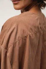 Blusa marrón de corte crop, escote en V y mangas largas anchas. Cierre frontal con lazos.