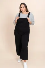 Mono enterizo negro de corte holgado, con tirantes ajustables y bolsillos delanteros.