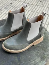 Botas Chelsea color verde oliva, combinadas en cuero liso y gamuza, con elásticos laterales color gris claro y tirador trasero.