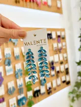 Aros colgantes plateados con forma de rama y cristales facetados color celeste.