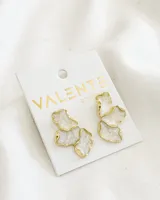 Par de aros colgantes con forma de flor irregular, con centro blanco marmolado y borde dorado.