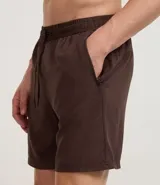 Bermuda deportiva masculina de poliéster reciclado certificado RCS, color negro, con cintura elástica y lazo ajustable. Presenta un estampado abstracto en tonos claros en la parte superior delantera.