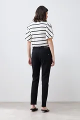 Pantalón de jean negro, corte slim fit, tiro medio y largo hasta el tobillo.