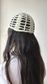 Gorro tipo beanie tejido al crochet con diseño calado y lentejuelas plateadas.