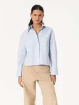 Camisa de poplín color celeste con bolsillos y puños con botones, de corte regular.
