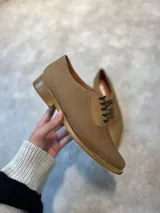 Zapato acordonado de cuero color tostado con punta fina y suela de madera.