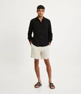 Camisa negra de lino con corte clásico, cuello camisero y mangas largas. Cierre frontal con botones.